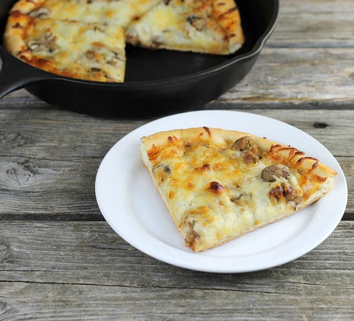 Skillet Sausage and Mushroom Pizza, made in cast iron skillet which makes for a soft chewy crust and then topped with sausage, mushrooms, and mozzarella cheese.