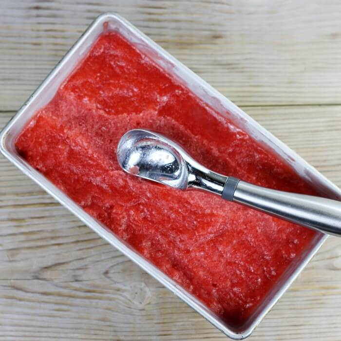 Looking down at a loaf pane with sorbet with an ice cream scoop.