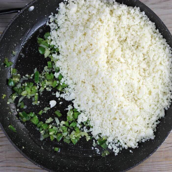 The cauliflower rice is added to the skillet.