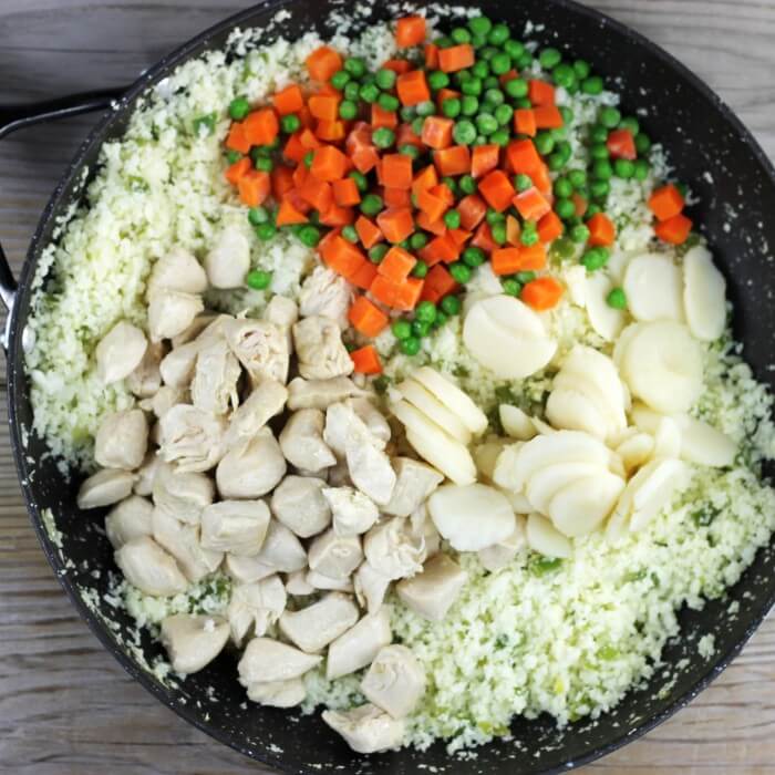 Cooked chicken, water chestnuts, pea and carrots are added to the skillet.