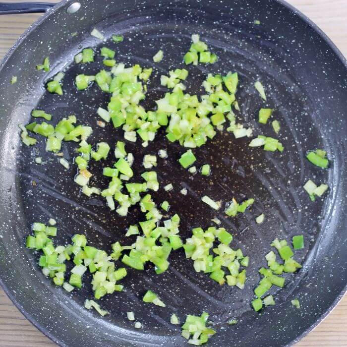 Overlooking a skillet with sauteed green peppers and onions.