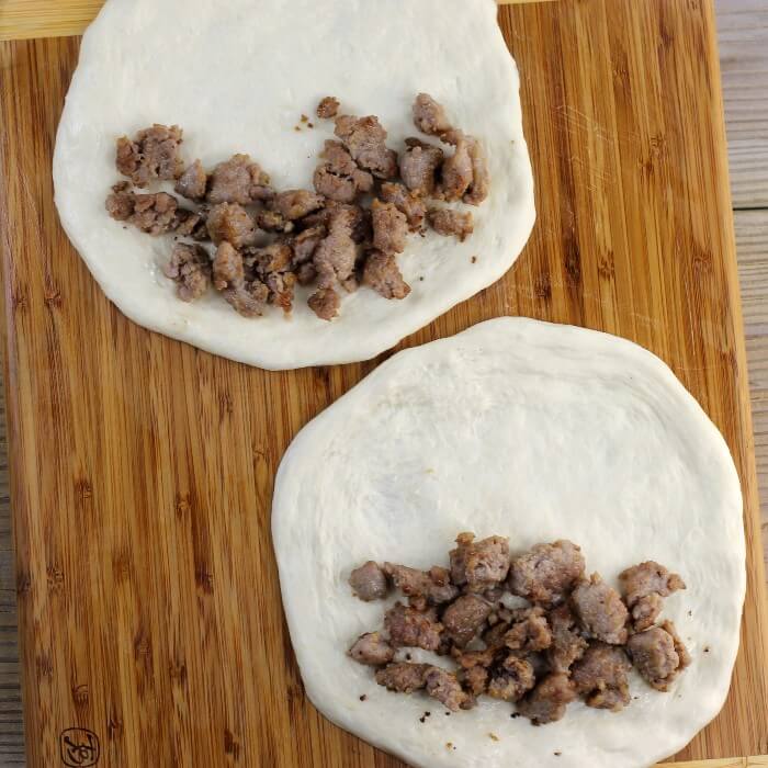 Pork sausage is placed on top of the dough circle. 