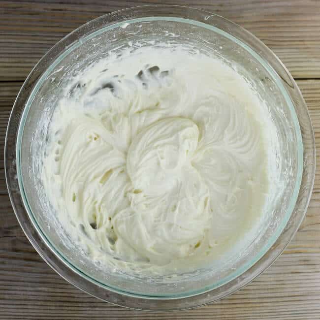 Cream cheese frosting is whipped up in a medium bowl.