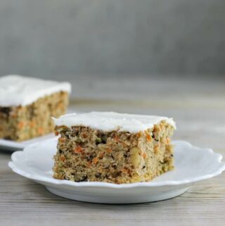 Looking at a side view of two pieces of carrot zucchini bars with cream cheese frosting.