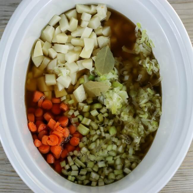 The broth is poured into the slow cooker with the vegetables. 