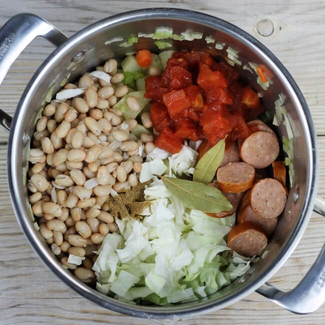 Beans, tomatoes, sausage, cabbage, bay leaves, and celery salt are added.