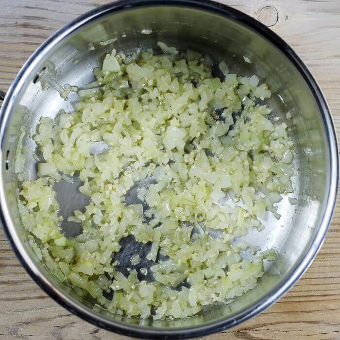 Looking down at cooked onion and garlic in a pot.