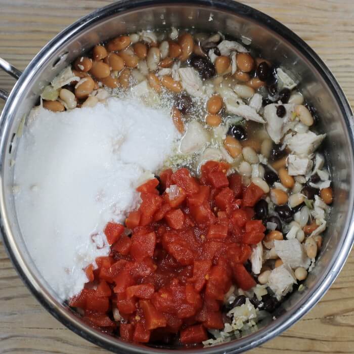 Coconut milk, chicken broth, and diced tomatoes are added to the kettle. 