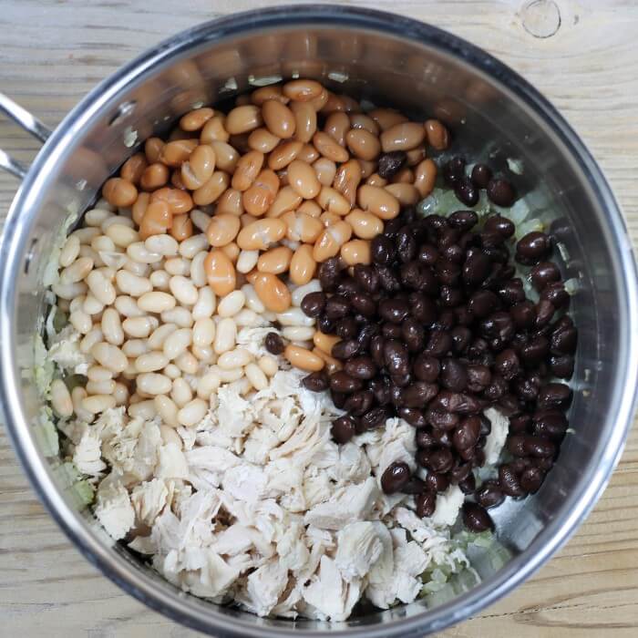 Cooked chicken and beans are added to the pot with the cooked onion.