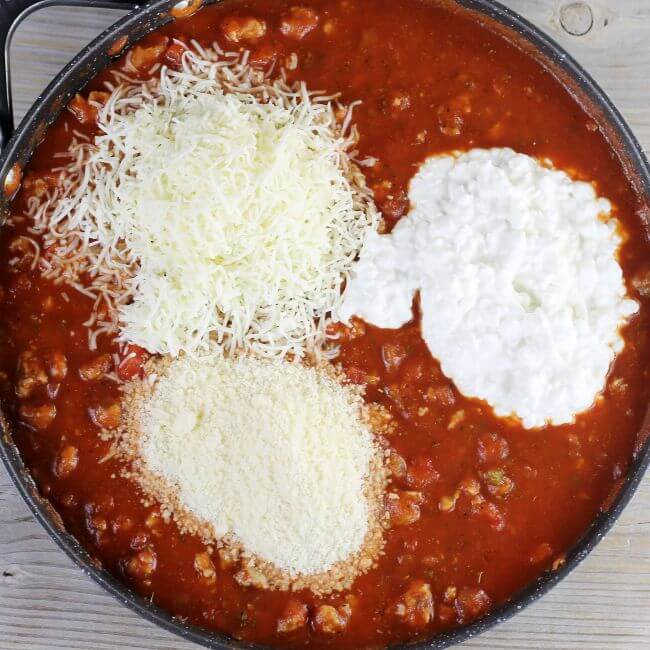 The cheeses are added to the skillet with the tomato sauce.