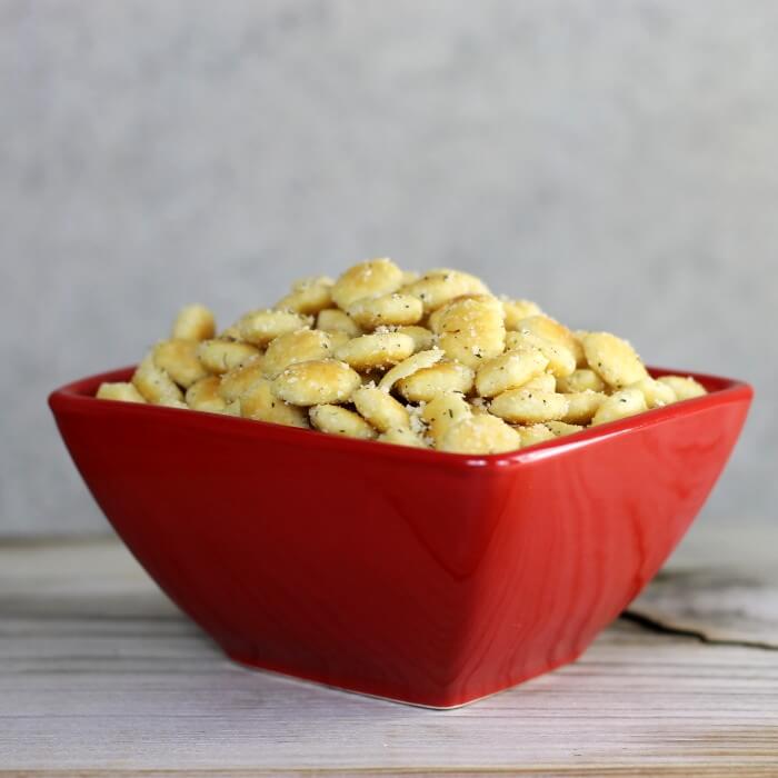 A side view of a red bowl filled with oyster crackers.
