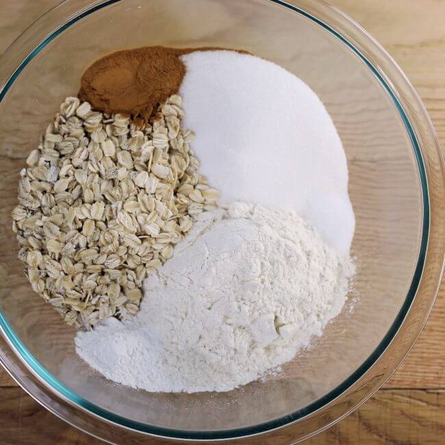Flour, oats, sugar, baking powder and cinnamon in a bowl.