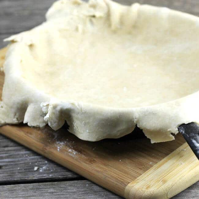 Pie crust lined skillet on a wood cutting board.