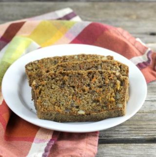 Slices of carrot quick bread on a white plate setting on a plaid napkin.