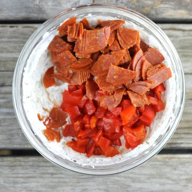 Glass bowl with cream cheese chopped pepperoni and roasted red peppers.