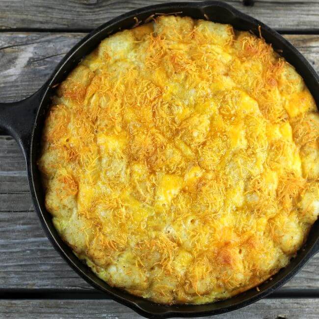 Golden tater tots with melted cheese in a cast-iron skillet