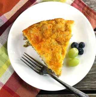 Egg bake on white plate with grapes, blueberry, and fork on a plaid napkin