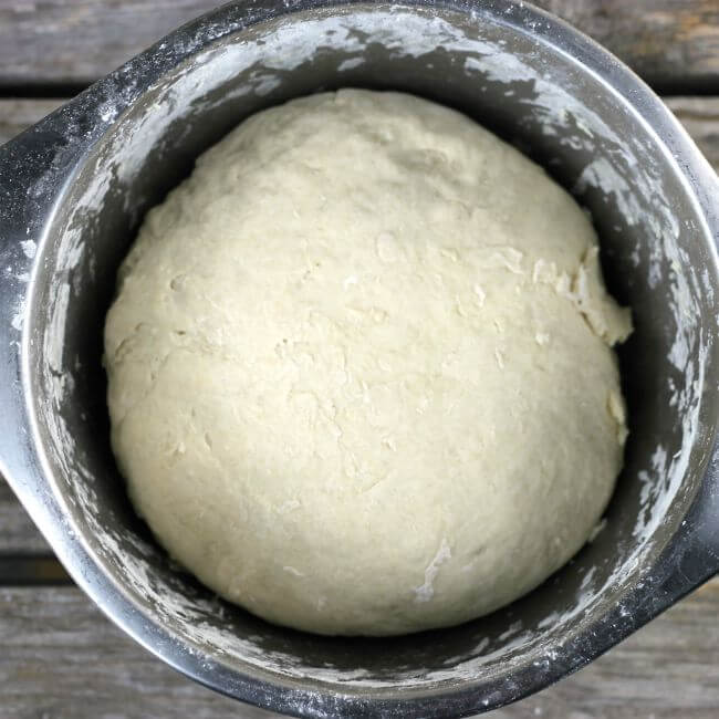 A stainless steel bowl with bread dough inside.