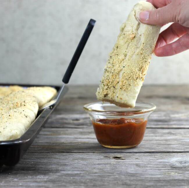 Breadstick being dunked into marinara sauce