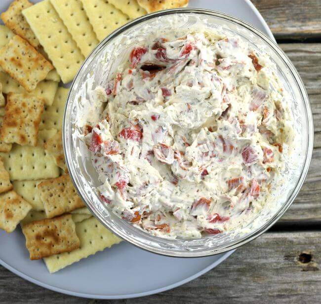 Pepperoni dip with crackers on a gray plate.