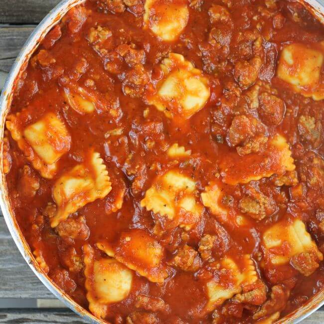 Cooked ravioli in meat sauce in a skillet.