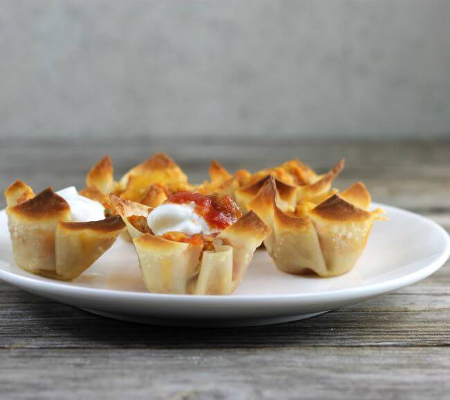 Side view of wonton taco cups on a white plate.