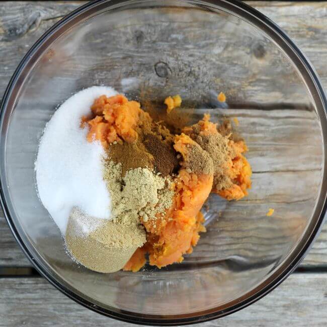 Sweet potato puree, sugar, and spices in a glass bowl.