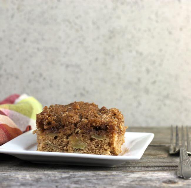 Apple cake on a white plate with plaid napkin and fork