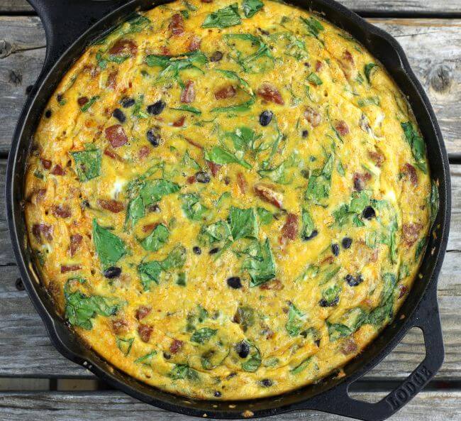 Baked chorizo frittata with spinach and black beans in a cast-iron skillet.