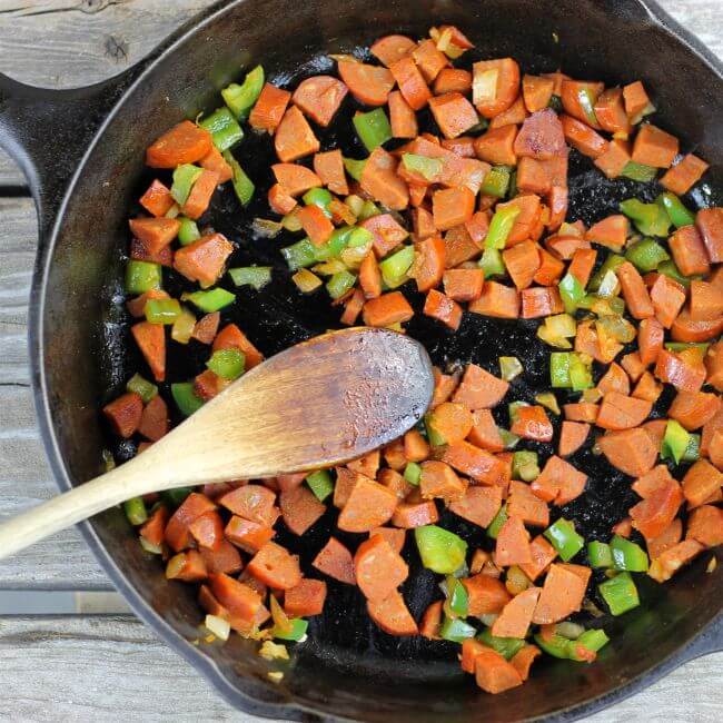 Cooked chorizo, green pepper, and onion in a cast-iron skillet.