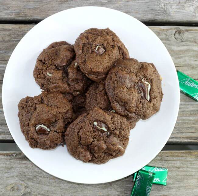 A plate of chocolate mint cookies with Andes mints on the side of the plate.