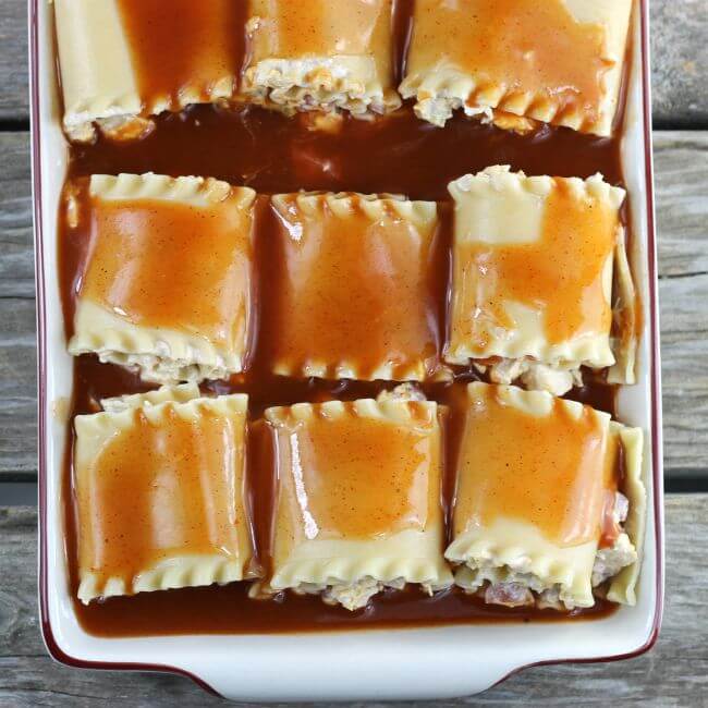 Unbaked chicken enchilada lasagna roll-ups in a baking pan.