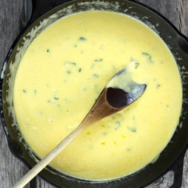 Cheese sauce in a skillet with a wooden spoon.