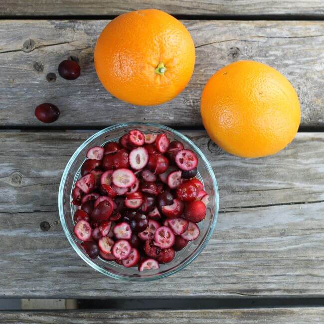 Oranges and a bowl of cranberries in a bowl.