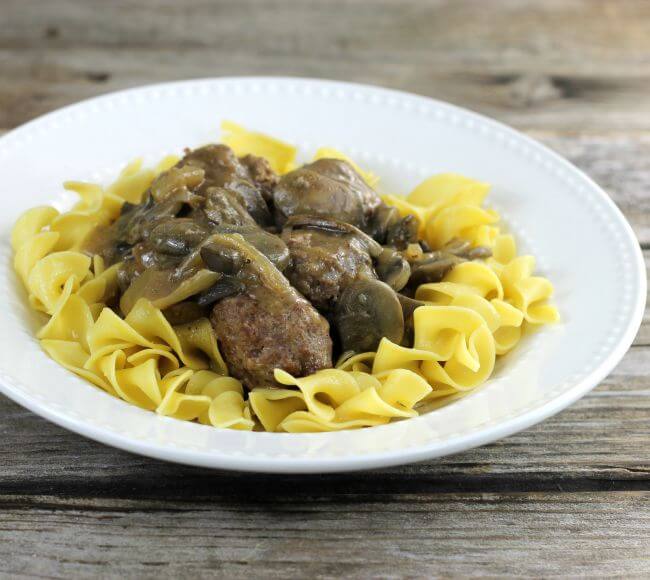 Side view of meatballs and noodles on a white plate.