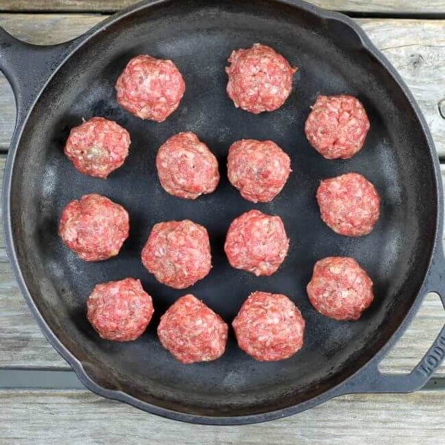 Raw meatballs in a skillet.