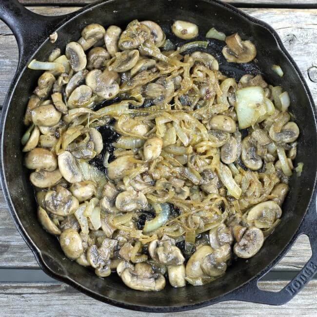 Cooked onion and mushrooms in a skillet.