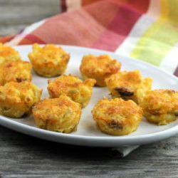 Macaroni and cheese bites on a white platter with a napkin in the back.