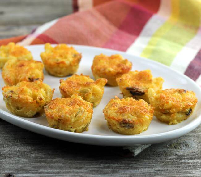 Macaroni and cheese bites on a white platter with a napkin in the back.