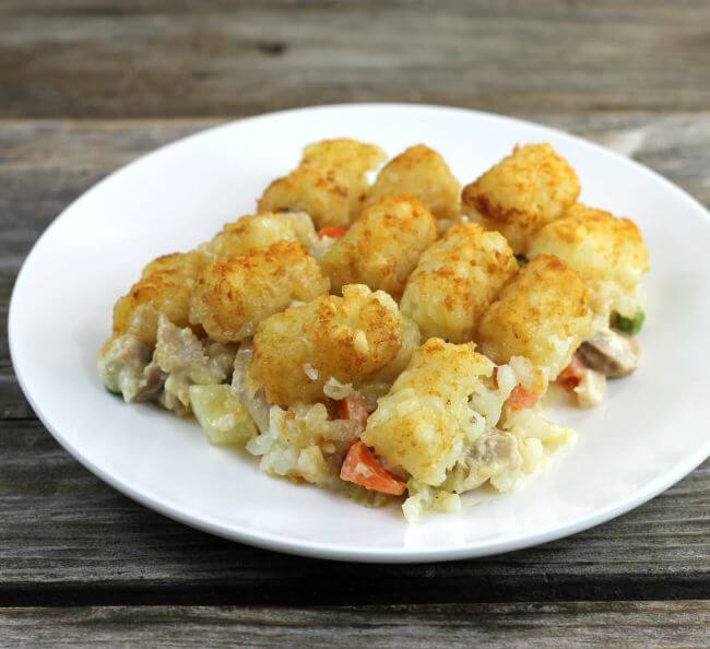 Side view of the tater tot chicken pot pie casserole on a white plate.