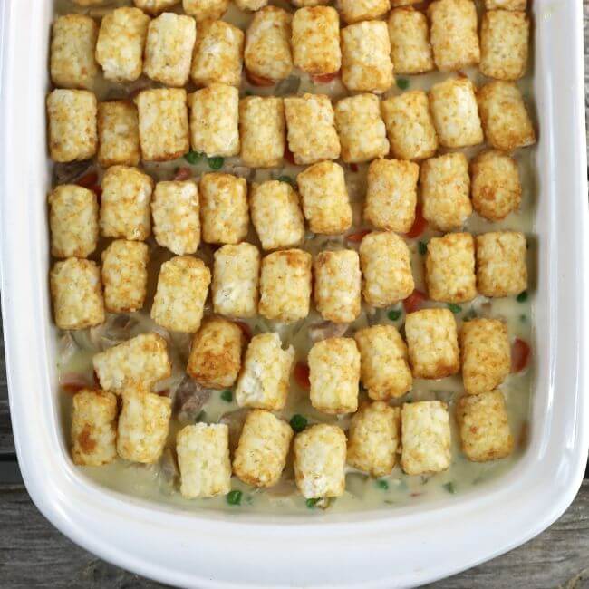 Tater tot are arranged over top of the filling for the tater tot chicken pot pie casserole.