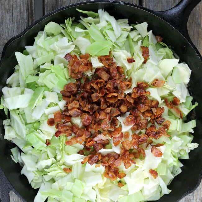 Add the cooked bacon to the cabbage in a skillet.