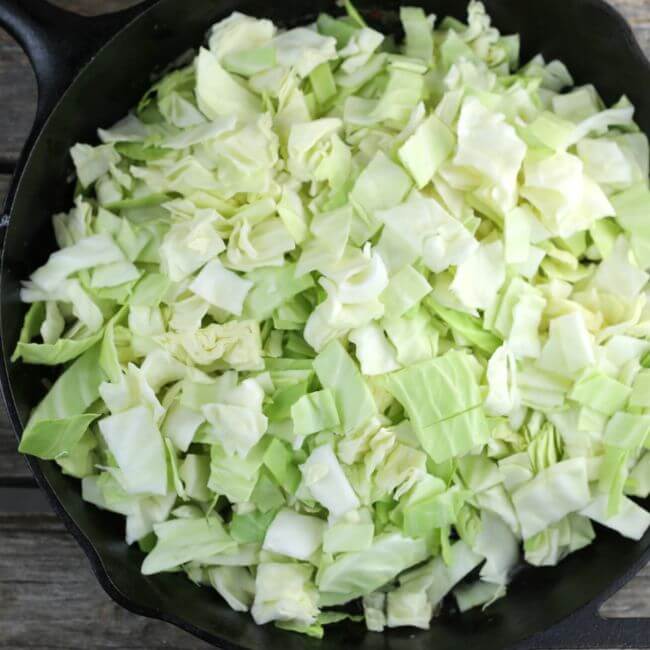Chopped cabbage added to the cast-iron skillet.