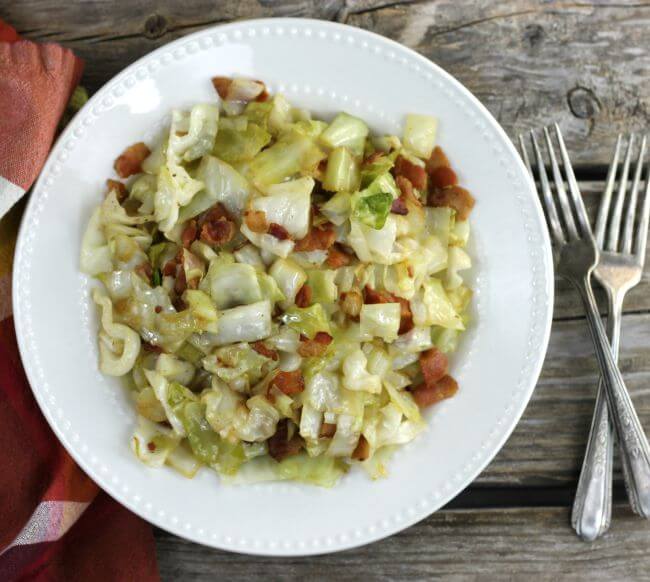 Cabbage in a white dish with a napkin and forks on the sides of the dish. 