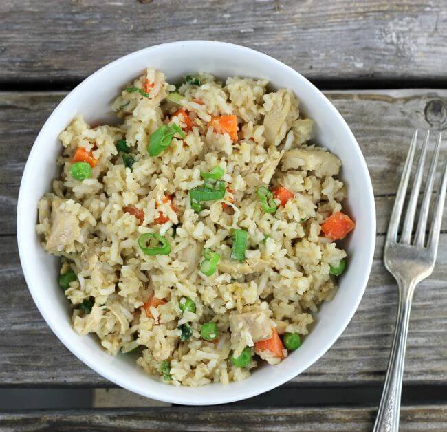 Looking down at a bowl of fried rice with a fork on the side.