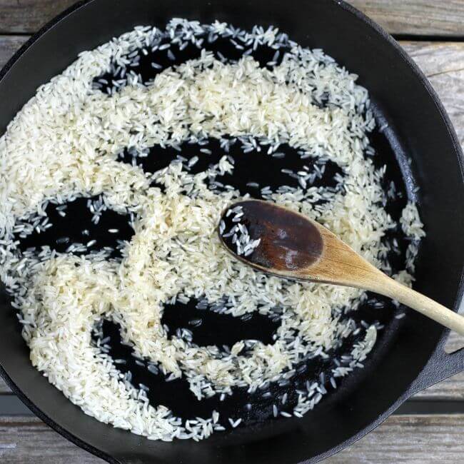 Rice in a cast-iron skillet with a wooden spoon.
