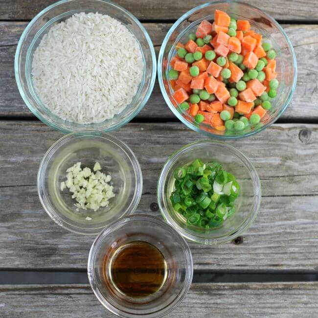 Vegetables, rice, and sesame seed oil in glass bowls.