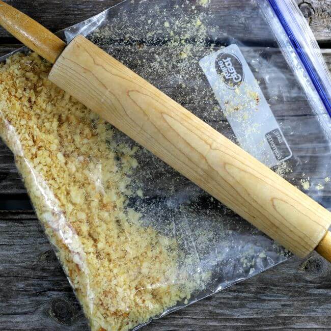 Crushing potato chips in a bag with a rolling pin.
