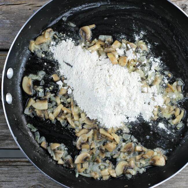 Flour added to a skillet with cooked onions in it.
