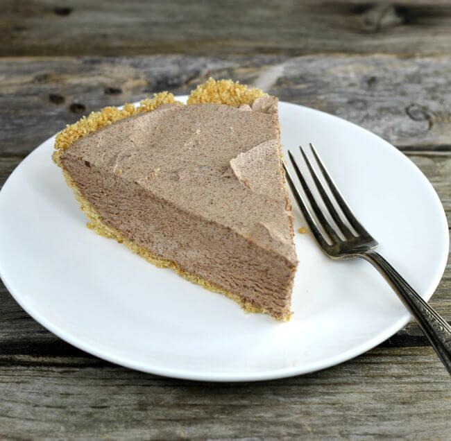 Chocolate pie on a white plate with a fork on side of the plate.